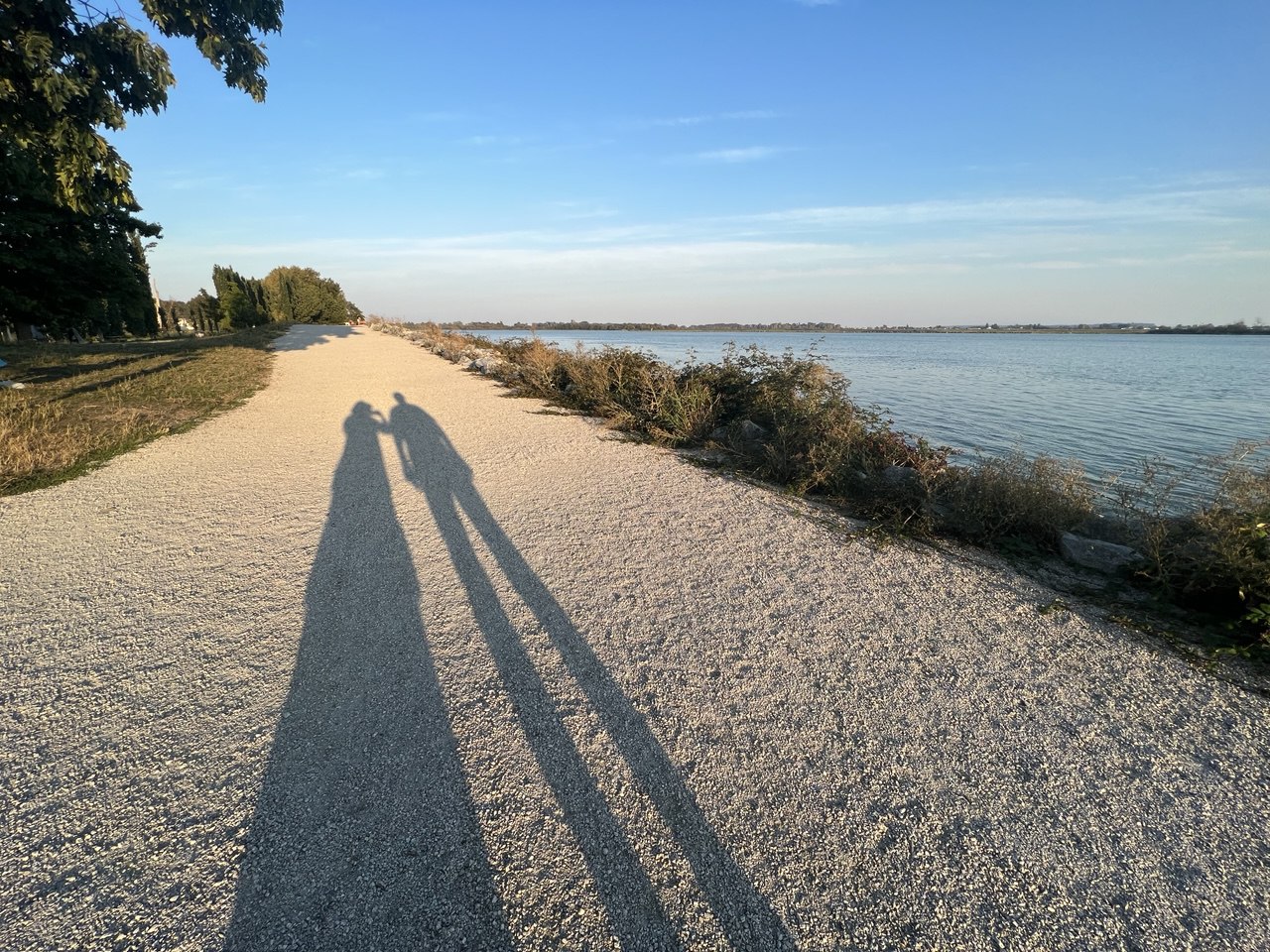 A waterfront path with long shadows — symbol of journey, relationship, and movement through life